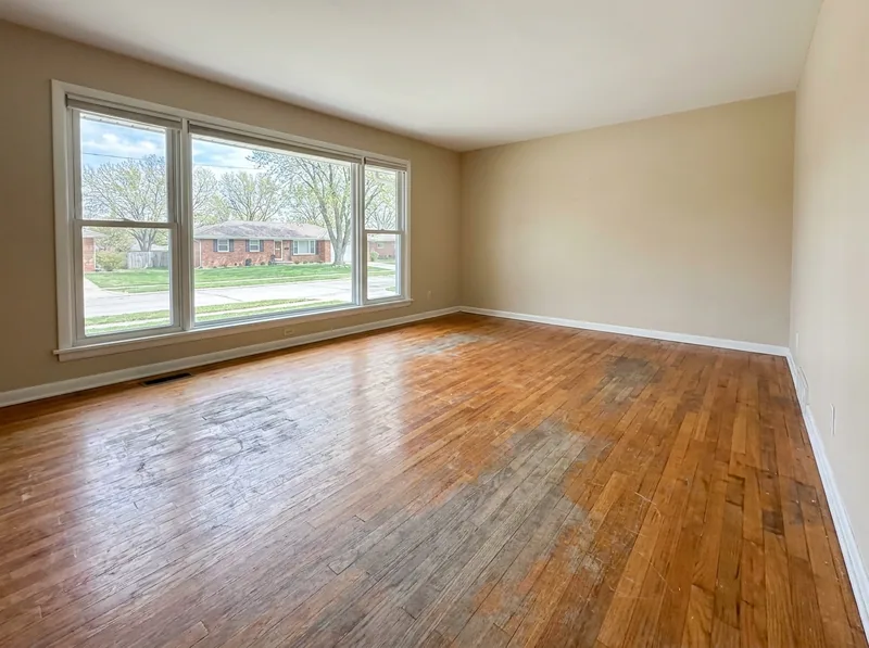 Living room red oak floor with gray worn traffic lanes, scratches and water marks before refinishing